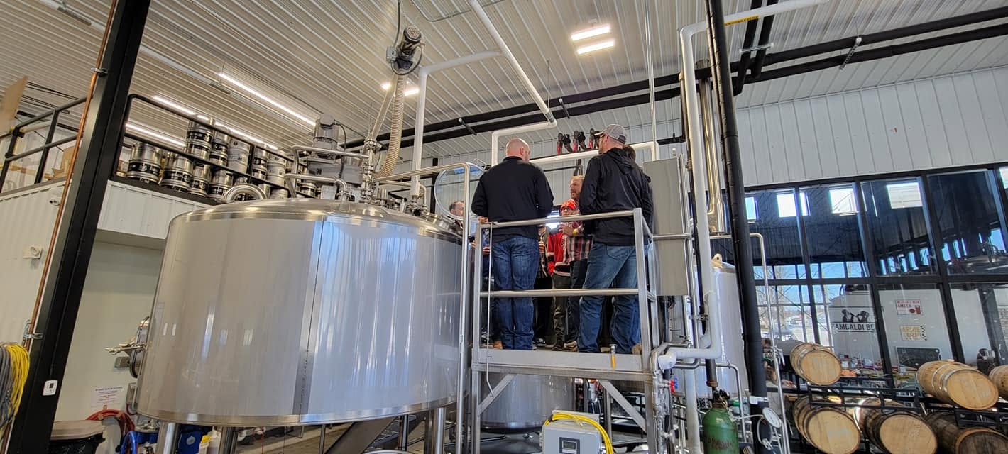 The group on the brewhouse catwalk among the tanks.